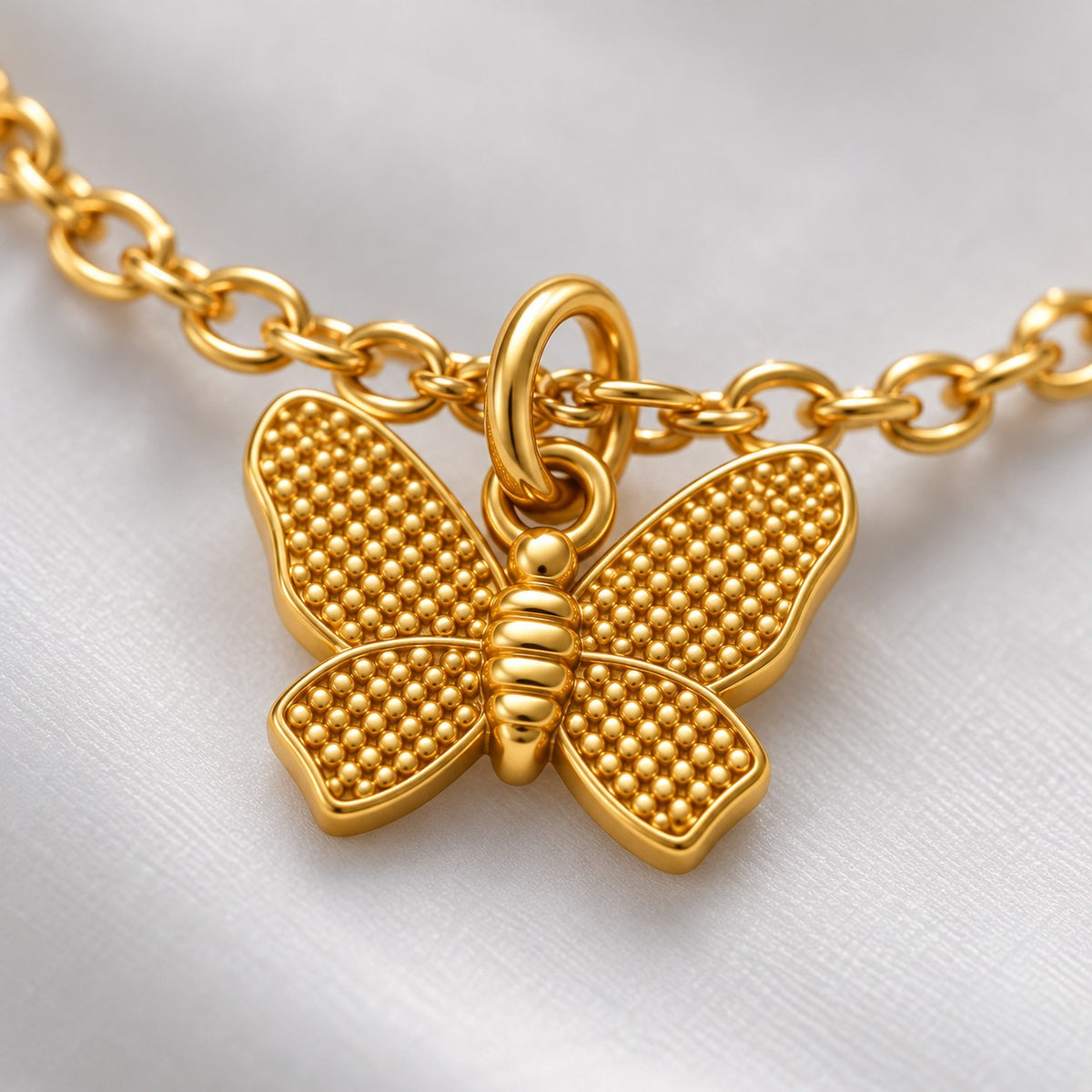 Close-up of the dotted-texture wings on the gold butterfly charm bracelet