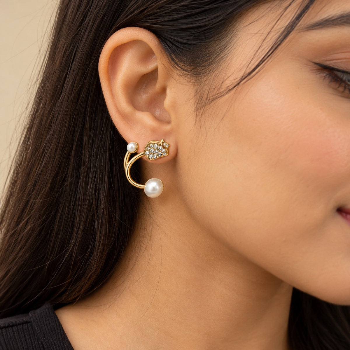 Woman wearing a gold pearl open hoop stud earring, close-up of ear and jawline