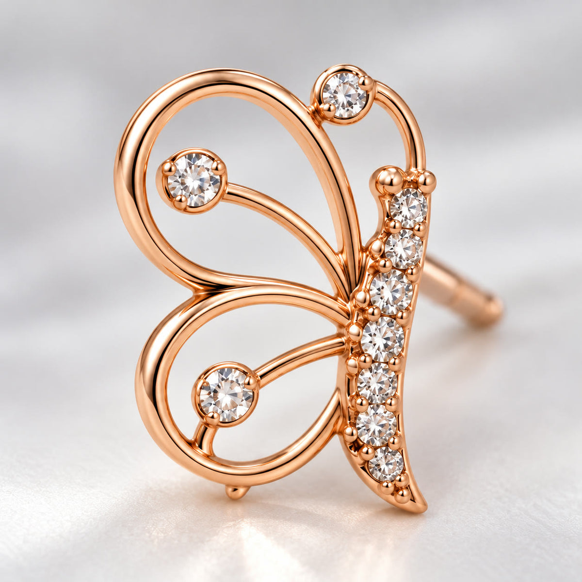 Close-up of the open-wire wings and crystal body of a rose gold butterfly stud earring