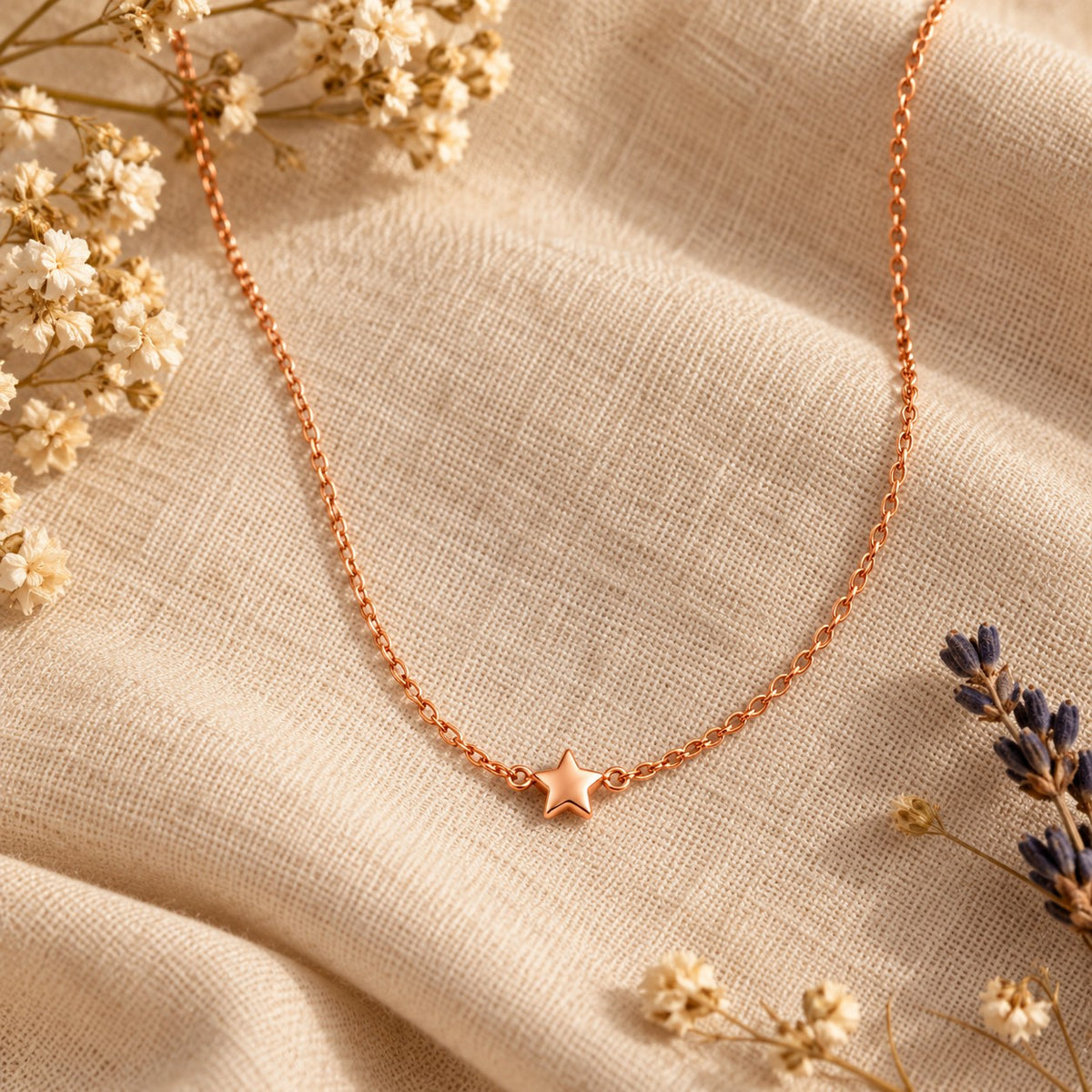 Rose gold star pendant chain necklace on linen with dried flowers