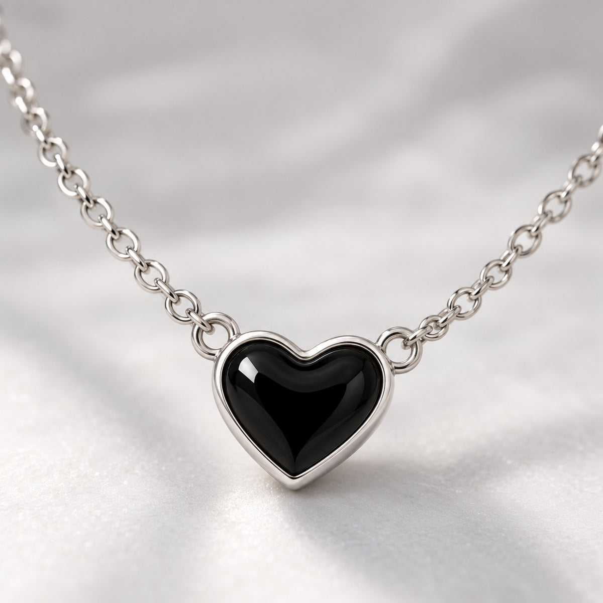 Close-up of the glossy black heart with silver-tone rim on the chain necklace