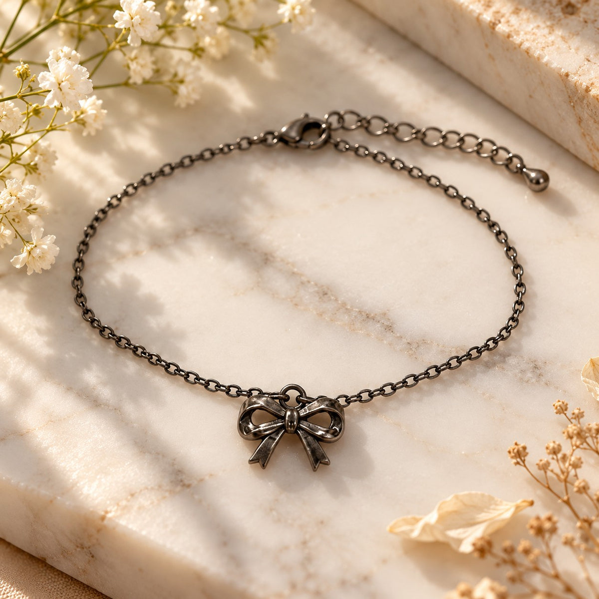 Silver bow charm bracelet styled on white marble with soft flowers
