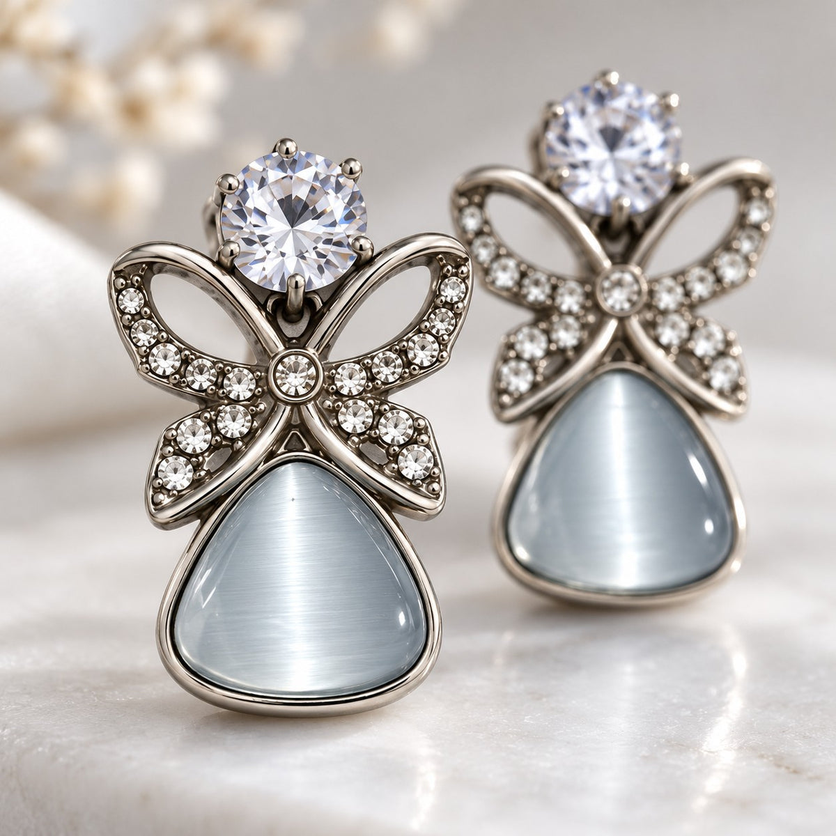 Macro detail of crystal butterfly and glowing cat eye stone on a silver drop earring
