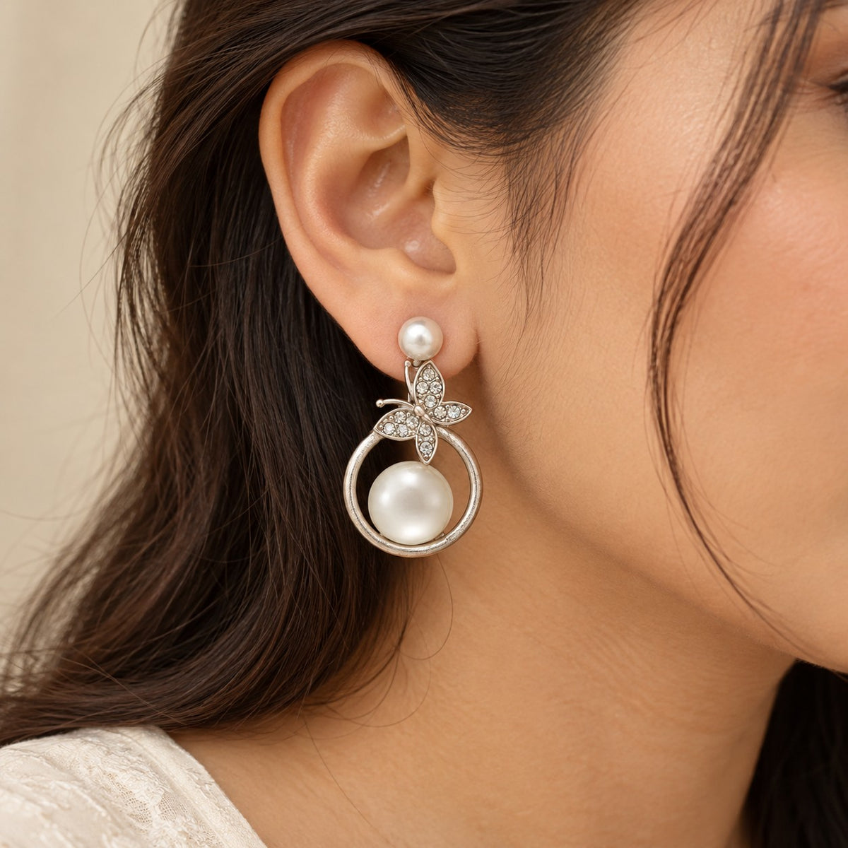 Woman wearing silver butterfly pearl circle drop earrings, ear and jawline close-up