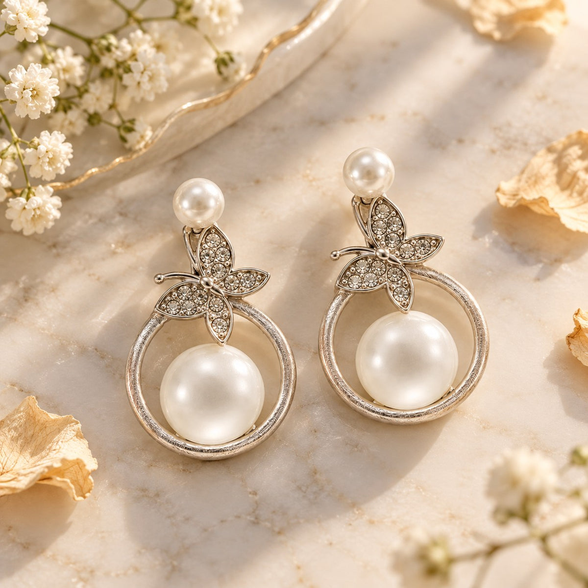 Silver butterfly pearl circle drop earrings on white marble with soft flowers