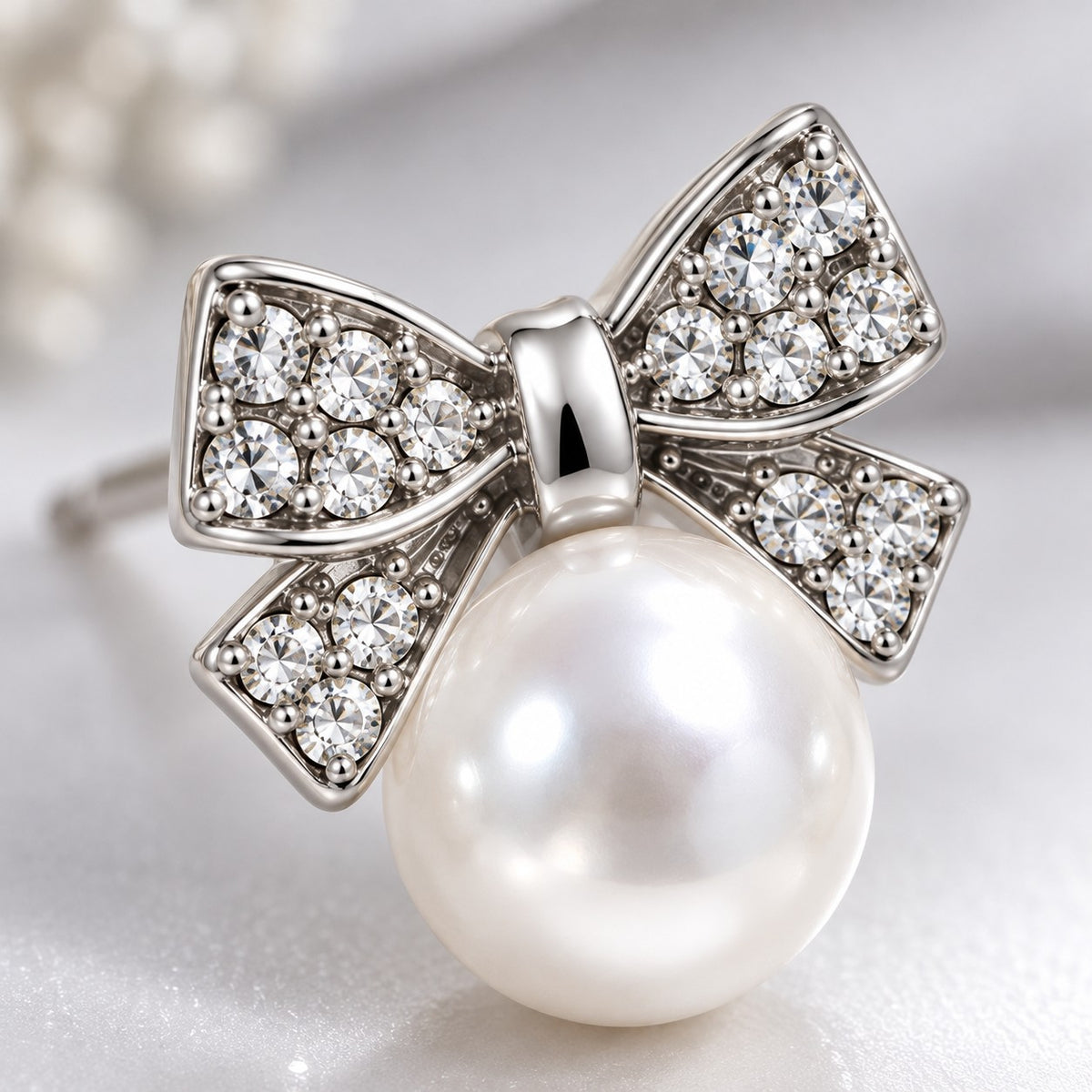 Macro detail of crystal-paved silver bow and faux pearl on a stud earring