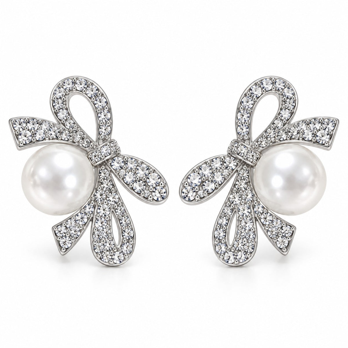 Silver crystal ribbon bow pearl drop earrings with large faux pearl on a white background