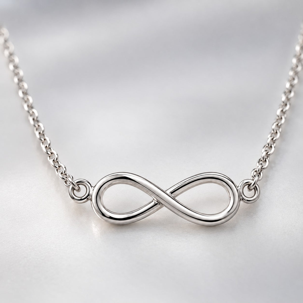 Macro view of the silver infinity pendant and fine twisted chain links