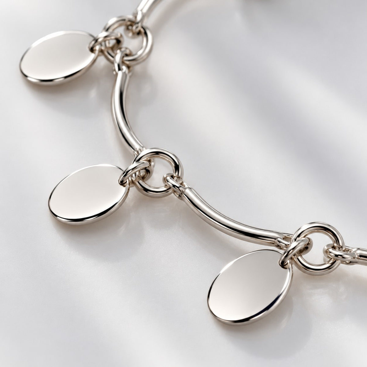 Close-up of the polished oval disc charms and bar links of the silver disc bracelet