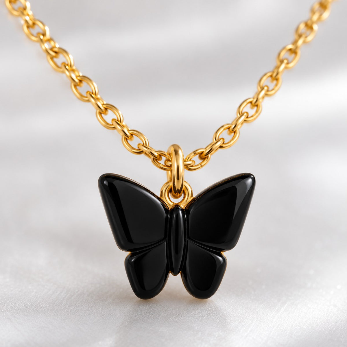 Close-up of the glossy black butterfly pendant on a gold-tone chain