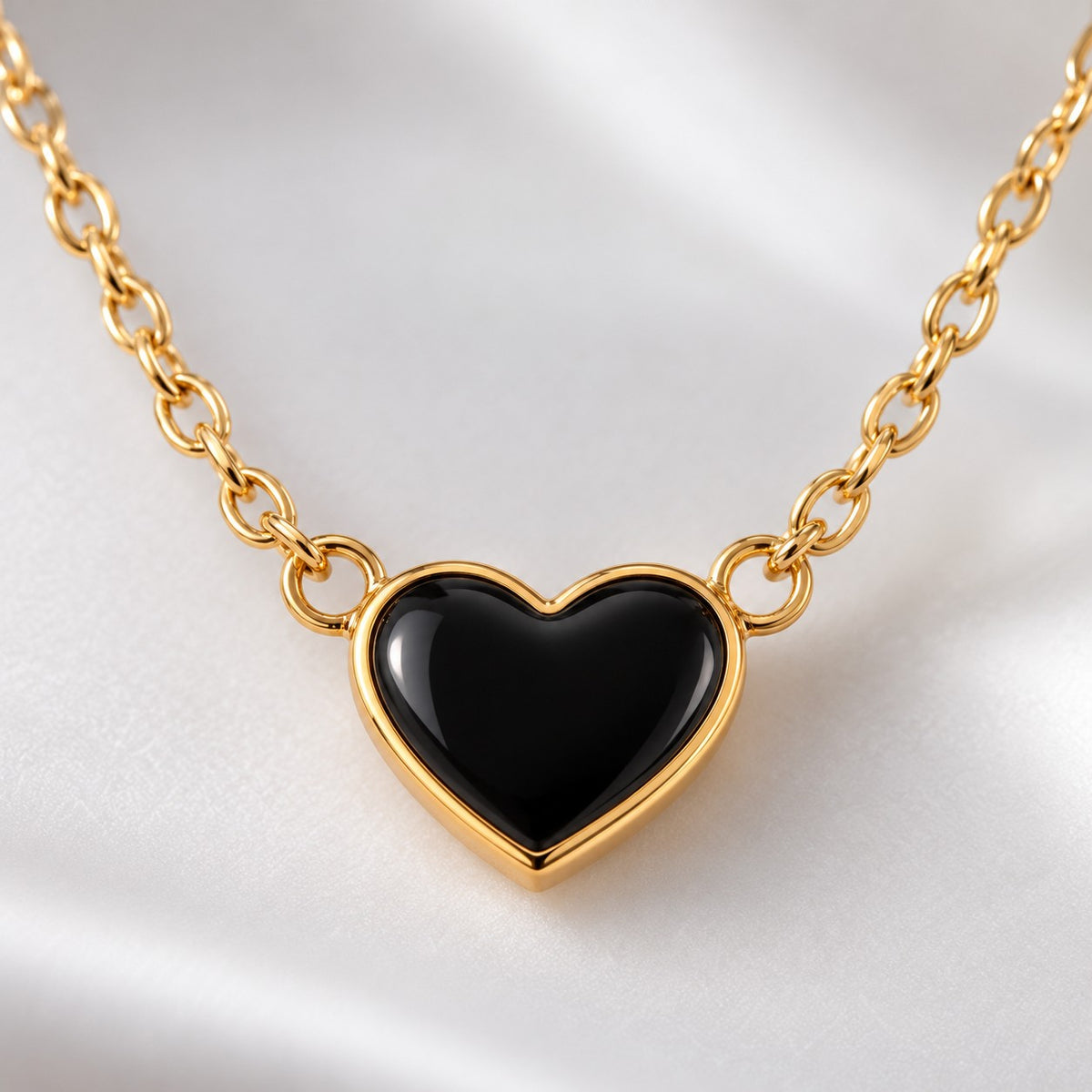 Close-up of the glossy black heart with gold-tone rim on the chain necklace