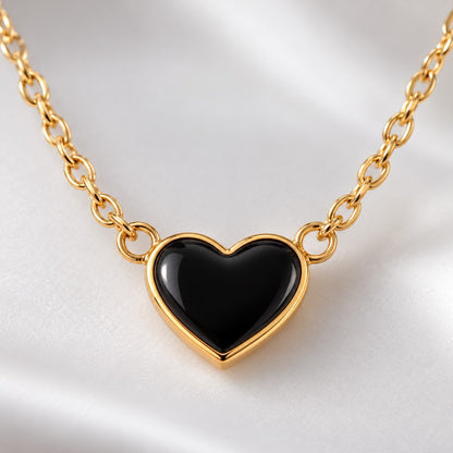 Close-up of the glossy black heart with gold-tone rim on the chain necklace