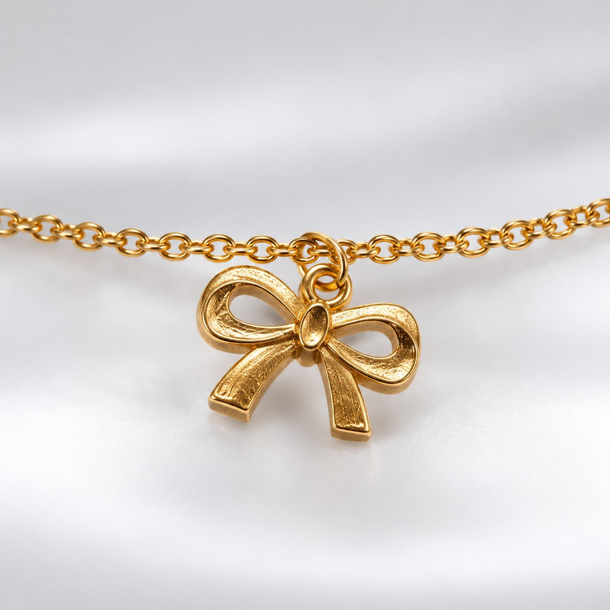 Close-up of the textured ribbon bow charm on the gold bow charm bracelet