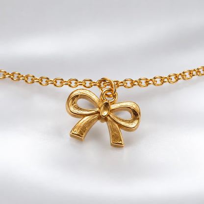Close-up of the textured ribbon bow charm on the gold bow charm bracelet