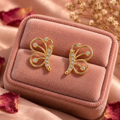 Gold butterfly stud earrings on a blush velvet jewellery box with dried rose petals
