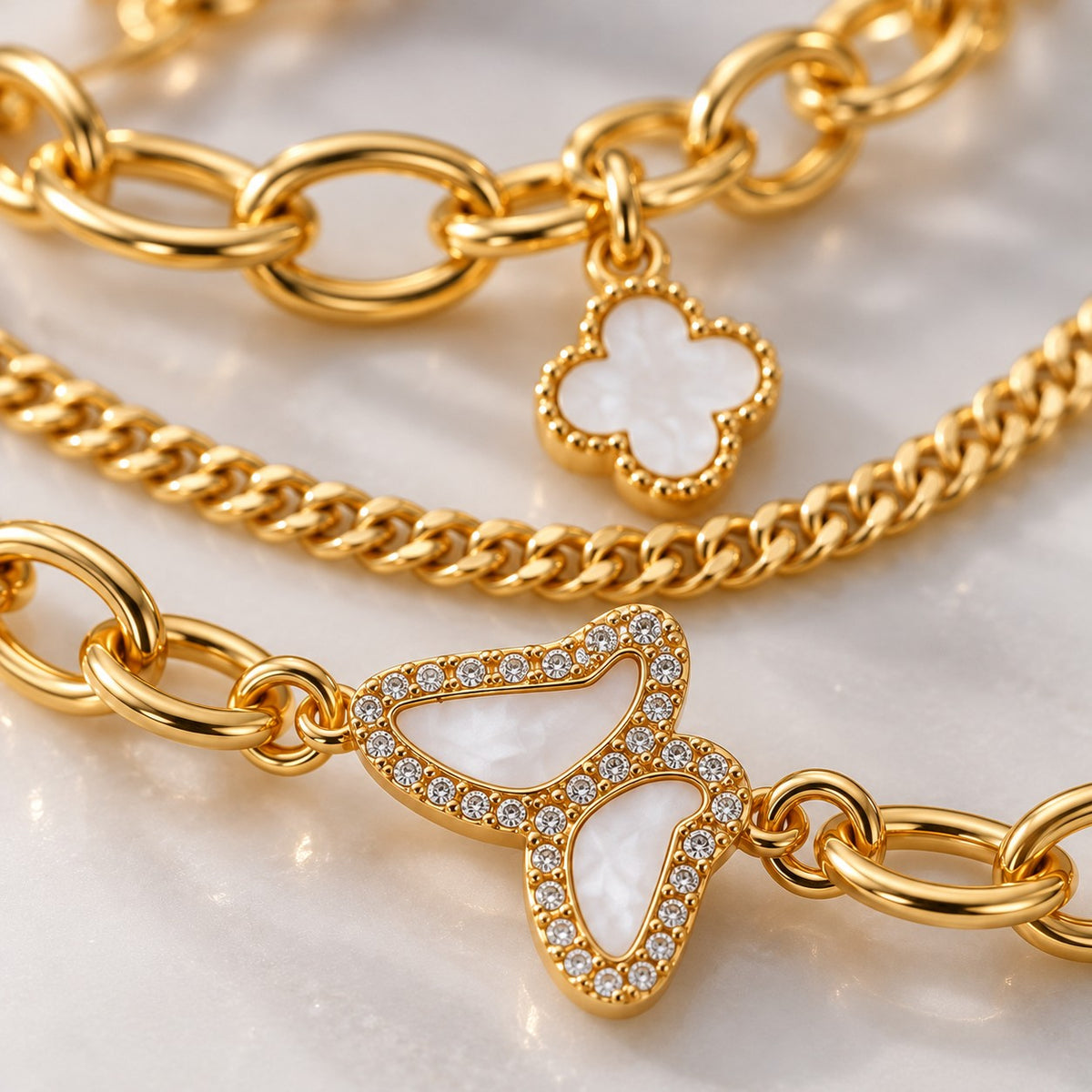 Close-up of the crystal butterfly and white clover charm on the gold bracelet set
