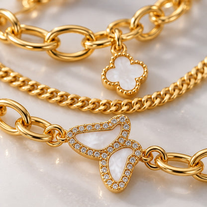 Close-up of the crystal butterfly and white clover charm on the gold bracelet set