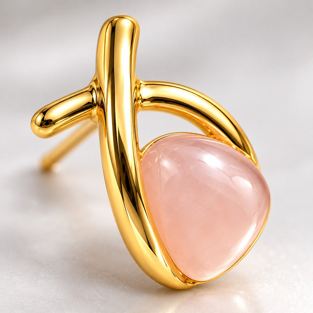 Close-up of the pale pink stone and crossed gold band on a crossover stud earring