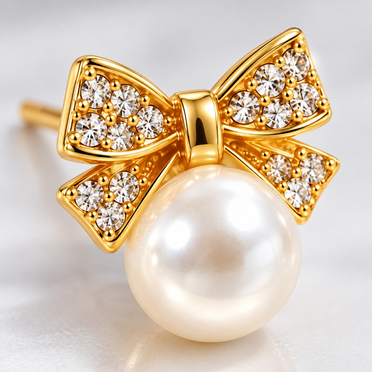 Macro detail of crystal-paved gold bow and faux pearl on a stud earring