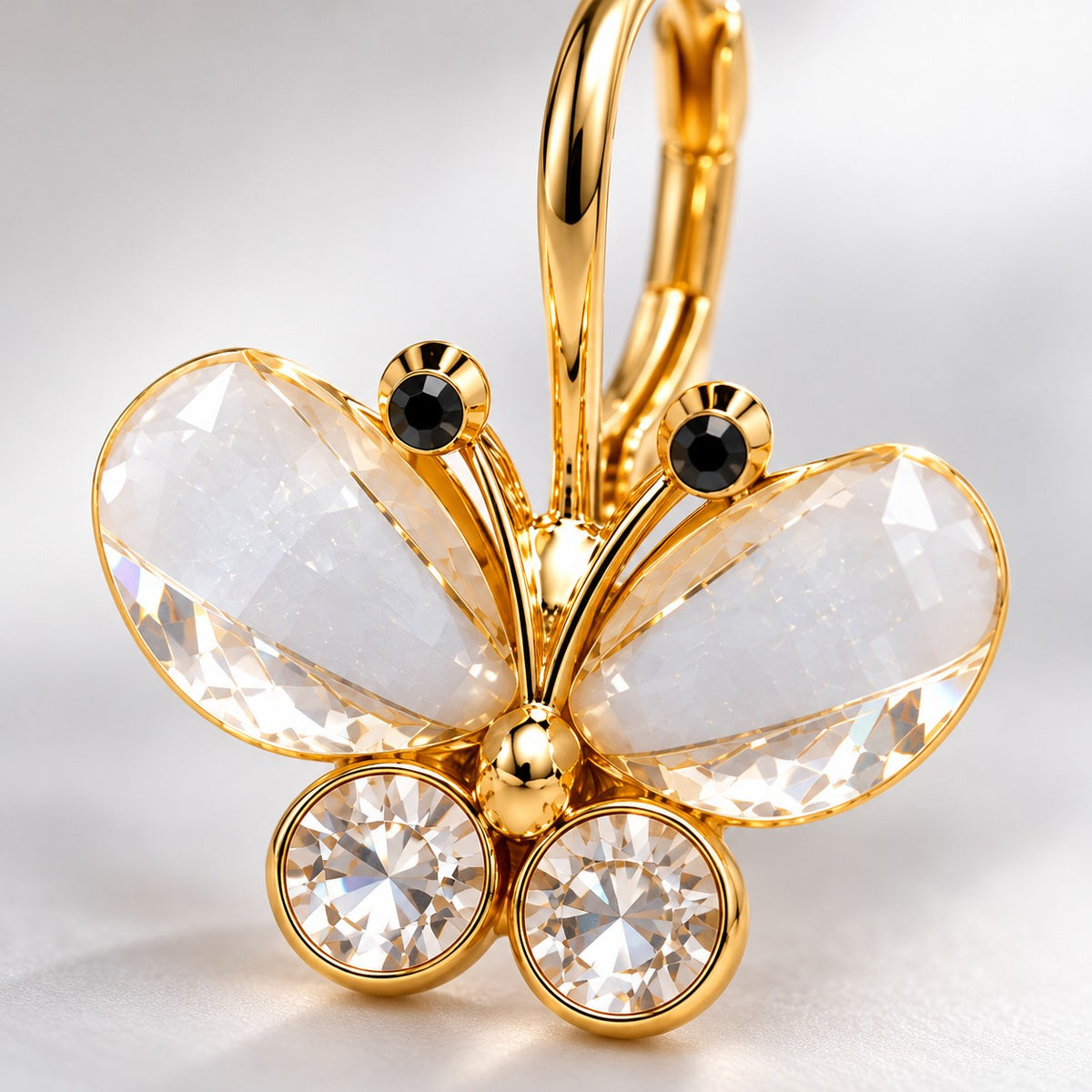 Close-up of pear crystal wings, round crystals and dark-tipped antennae on a gold butterfly earring