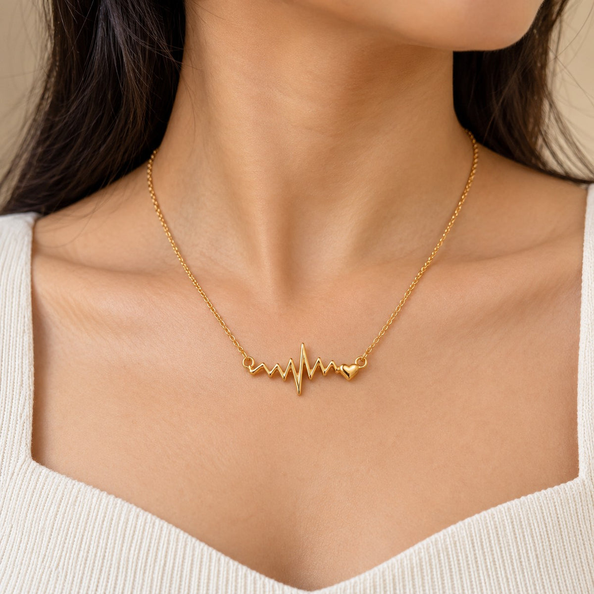 Woman wearing a gold heartbeat ECG pendant chain necklace