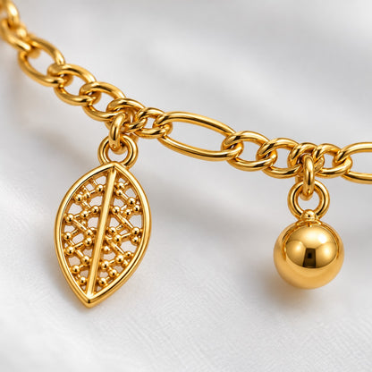 Close-up of the filigree leaf charm and gold bead drop on the gold anklet