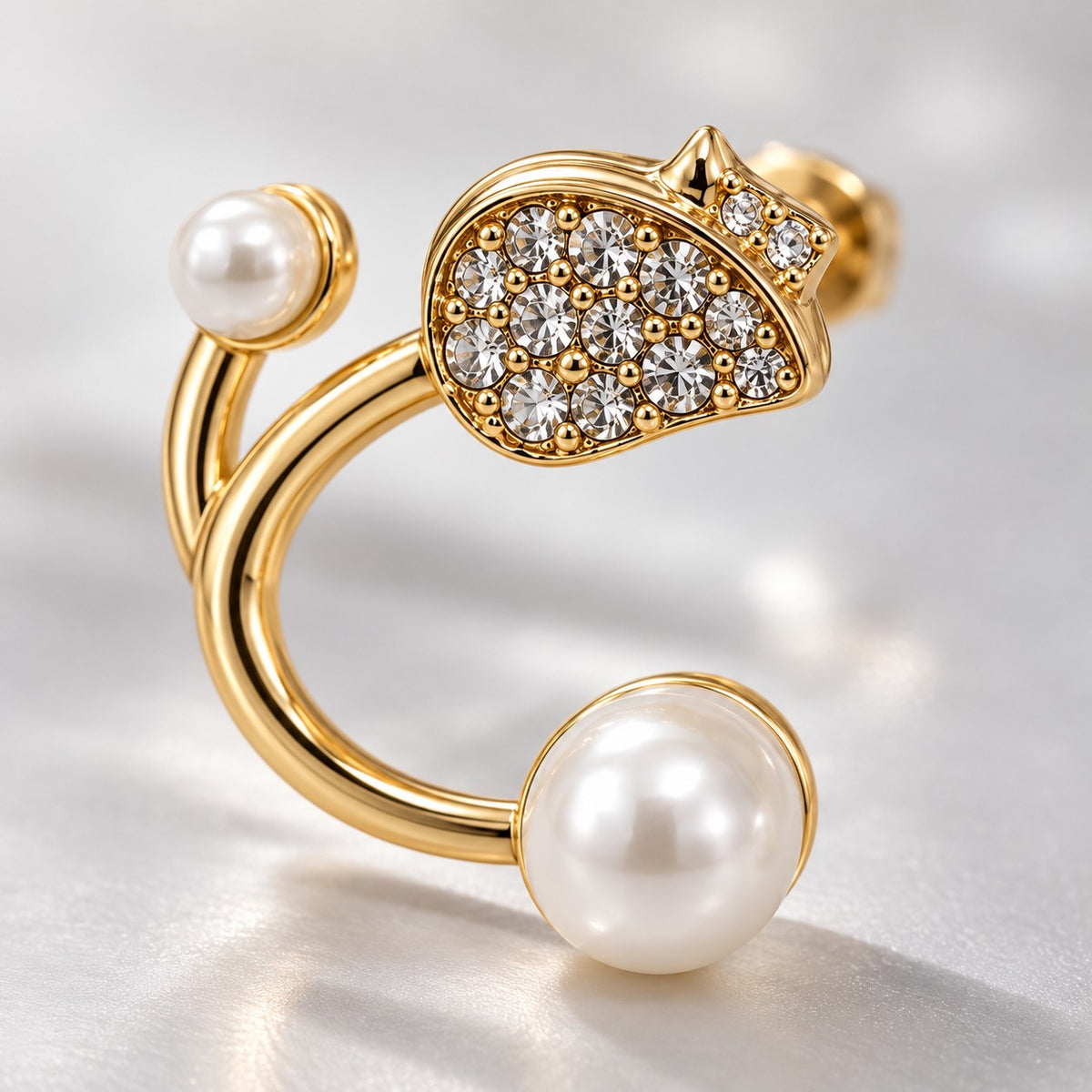 Close-up of the crystal pave stud and faux pearl ends on a gold open hoop earring