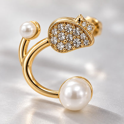 Close-up of the crystal pave stud and faux pearl ends on a gold open hoop earring