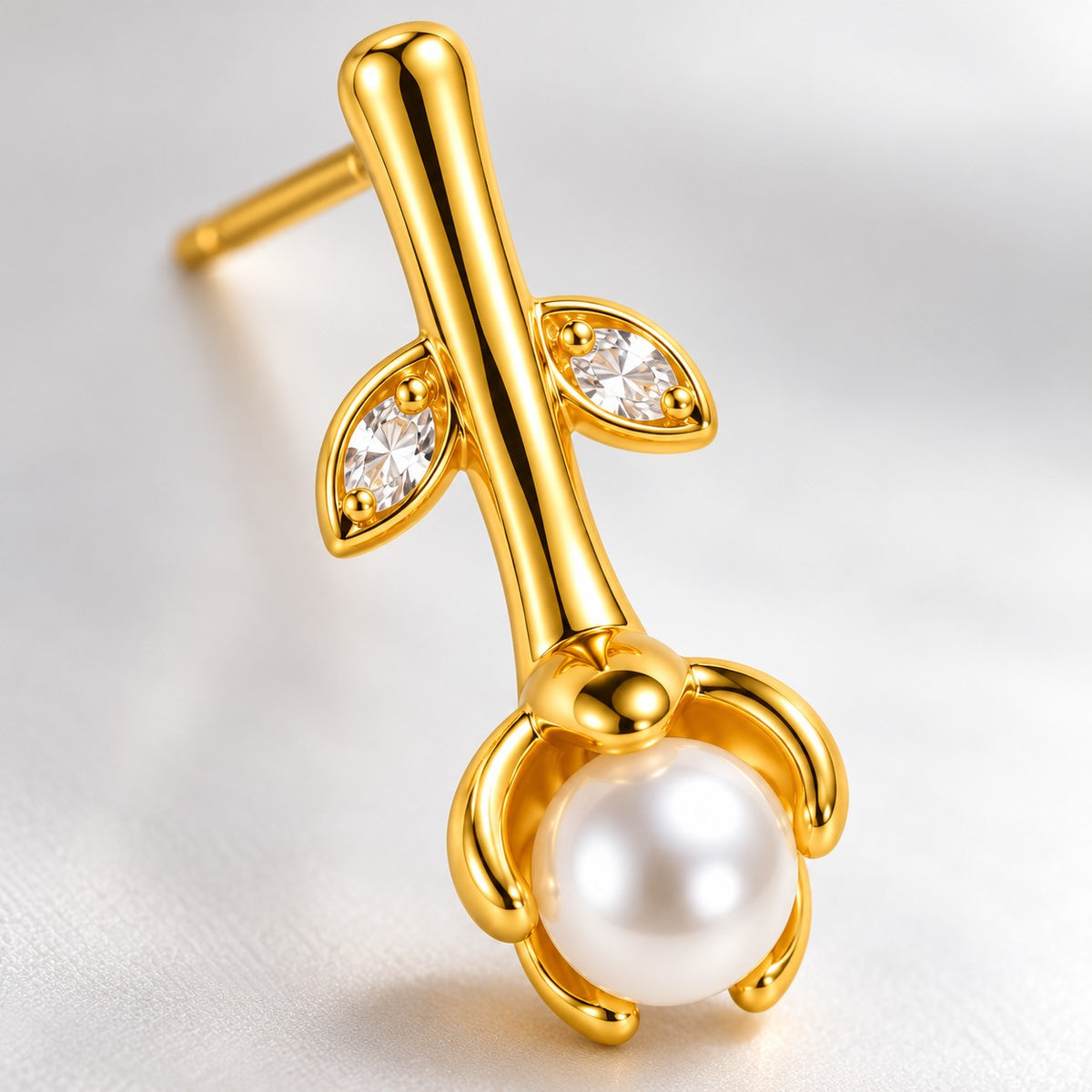 Close-up of the crystal leaves and petal-cupped faux pearl on a gold drop earring