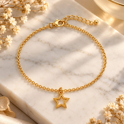 Gold star charm bracelet styled on white marble with soft flowers