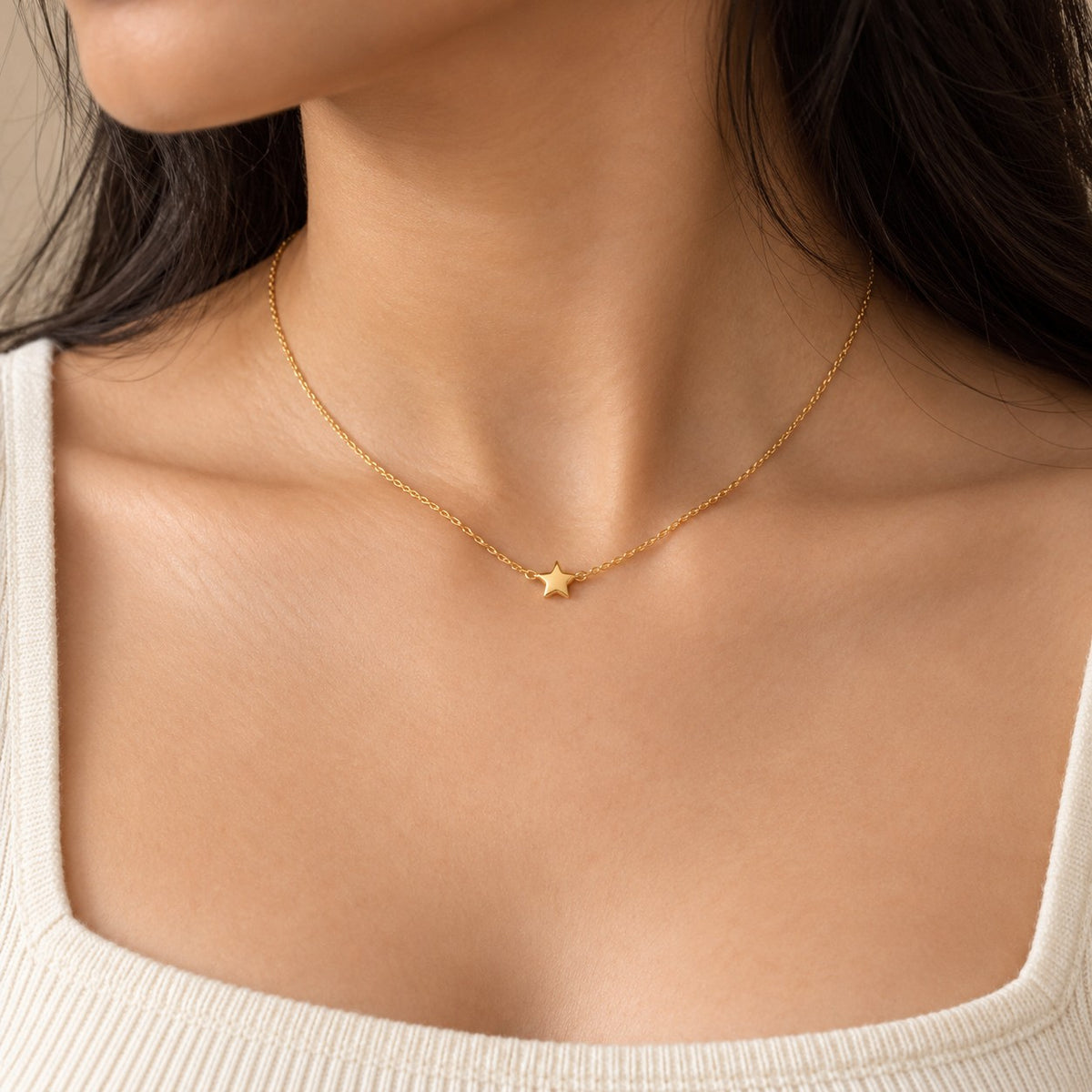 Woman wearing a dainty gold chain necklace with a tiny star pendant