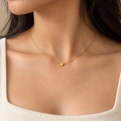 Woman wearing a dainty gold chain necklace with a tiny star pendant