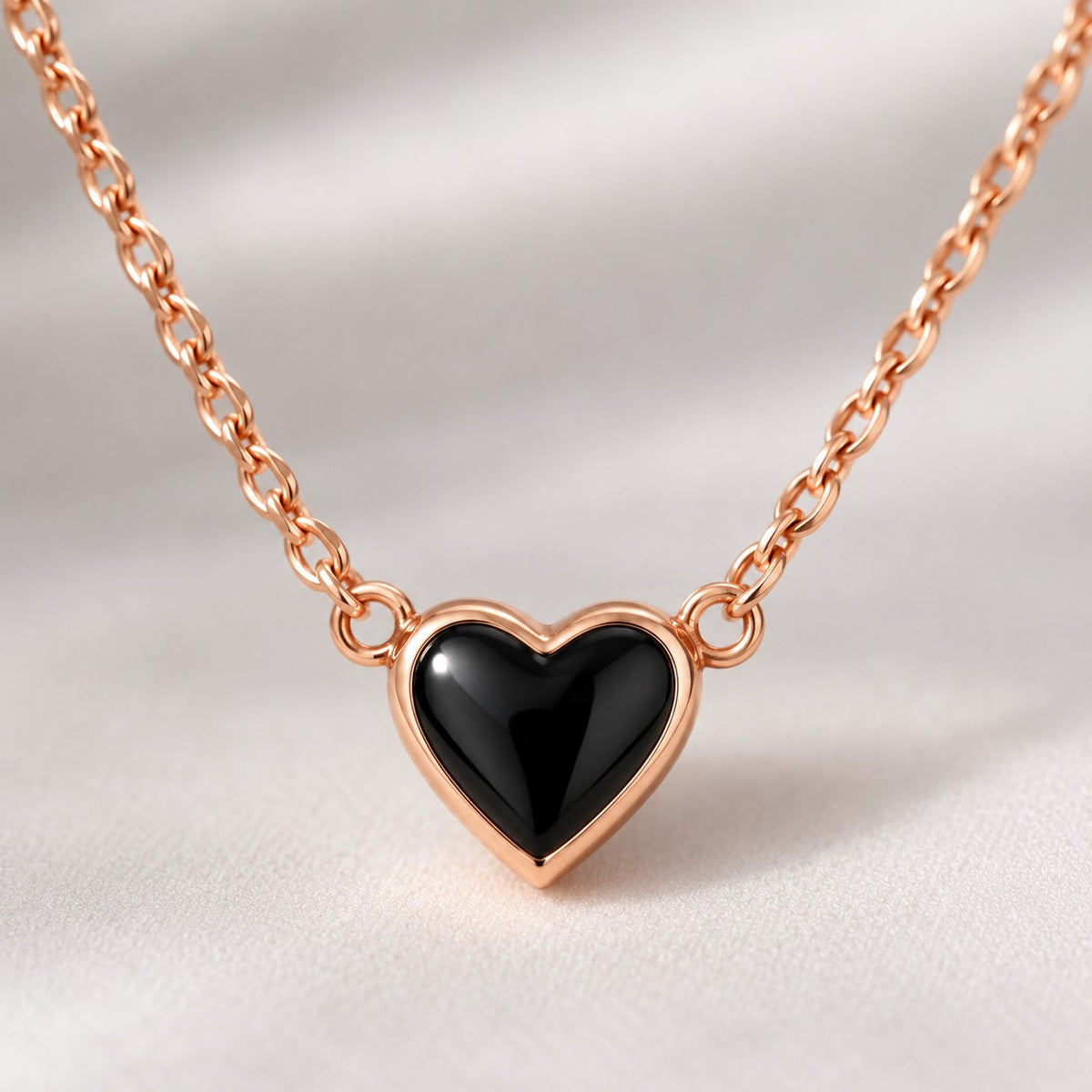 Close-up of the glossy black heart with rose gold-tone rim on the chain necklace