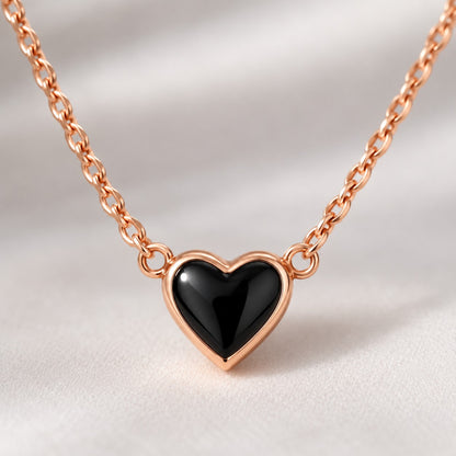 Close-up of the glossy black heart with rose gold-tone rim on the chain necklace