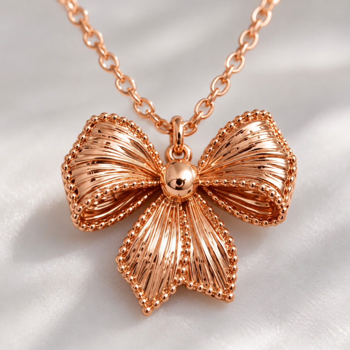 Close-up of the ribbed rose gold bow pendant with beaded edges