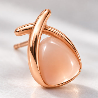 Close-up of the milky peach stone and crossed rose gold band on a stud earring