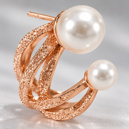 Macro of rose gold twisted bands and faux pearls on a double pearl hoop stud earring