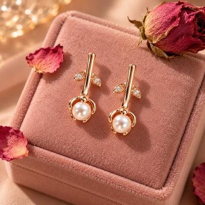 Rose gold rosebud pearl drop earrings on a blush velvet jewellery box with petals