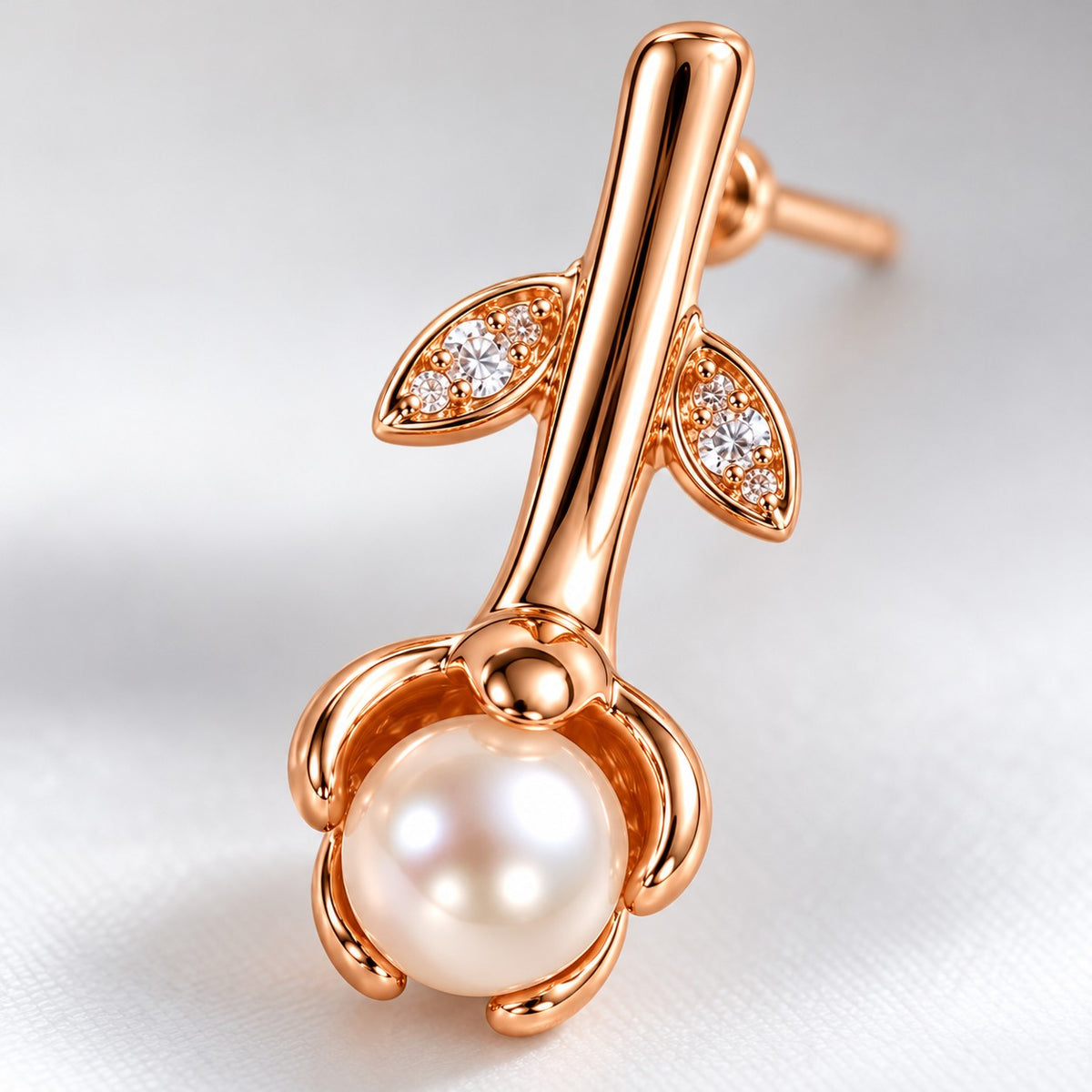 Close-up of the crystal leaves and petal-cupped faux pearl on a rose gold drop earring