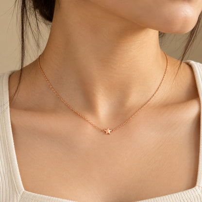 Woman wearing a dainty rose gold chain necklace with a tiny star pendant
