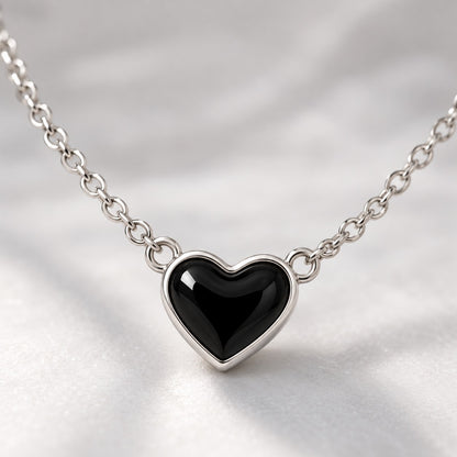 Close-up of the glossy black heart with silver-tone rim on the chain necklace