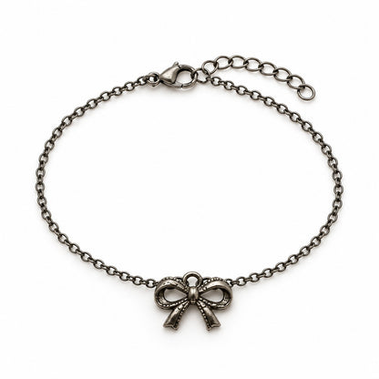 Silver bow charm bracelet with an antique ribbon bow charm on a white background