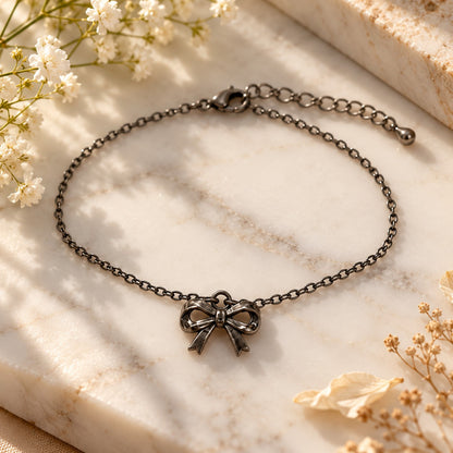 Silver bow charm bracelet styled on white marble with soft flowers