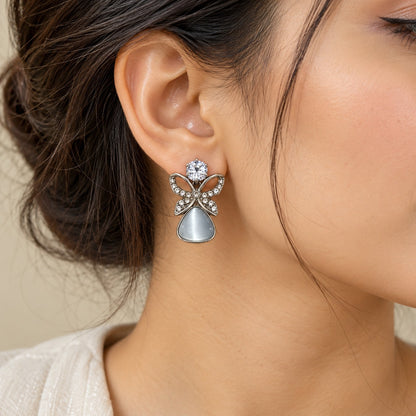 Woman wearing silver butterfly cat eye stone drop earrings, close-up of ear and jawline