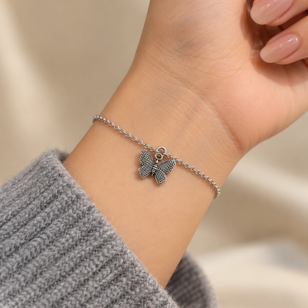 Woman wearing the silver butterfly charm bracelet on her wrist