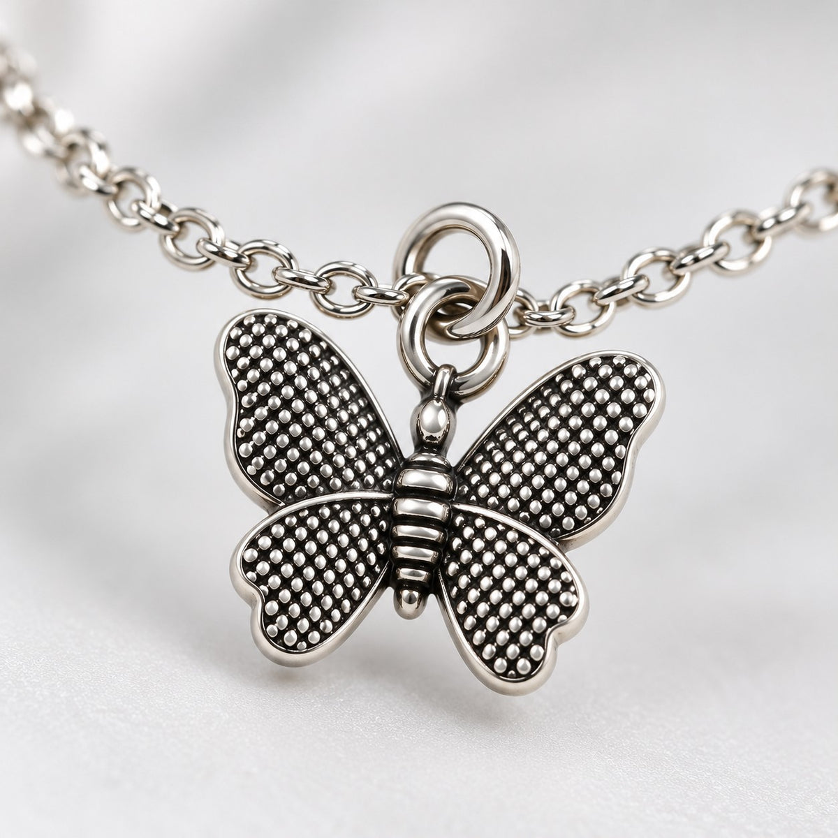 Close-up of the dotted-texture wings on the silver butterfly charm bracelet
