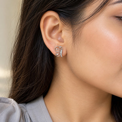 Woman wearing a silver butterfly stud earring with crystals, close-up of ear