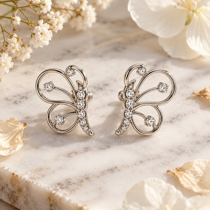 Silver butterfly stud earrings on white marble with soft dried flowers