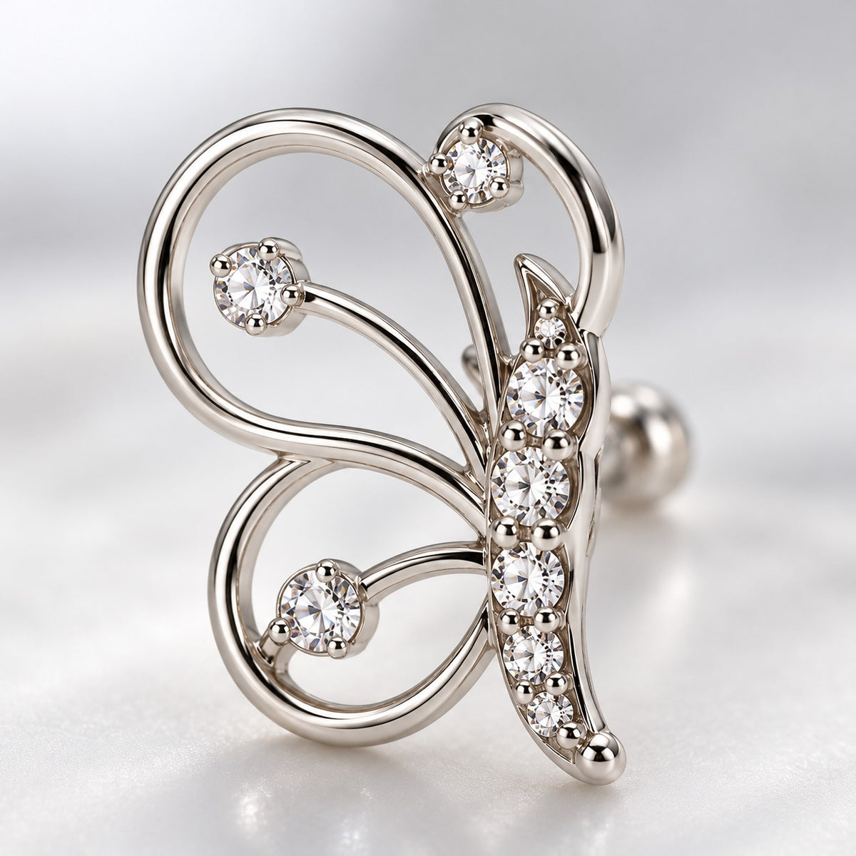 Close-up of the open-wire wings and crystal body of a silver butterfly stud earring
