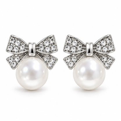 Silver crystal bow pearl stud earrings with faux pearl drop on a white background